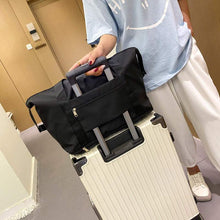 Load image into Gallery viewer, Foldable black travel bag atop a suitcase, showcasing its spacious design and convenient suitcase attachment feature.
